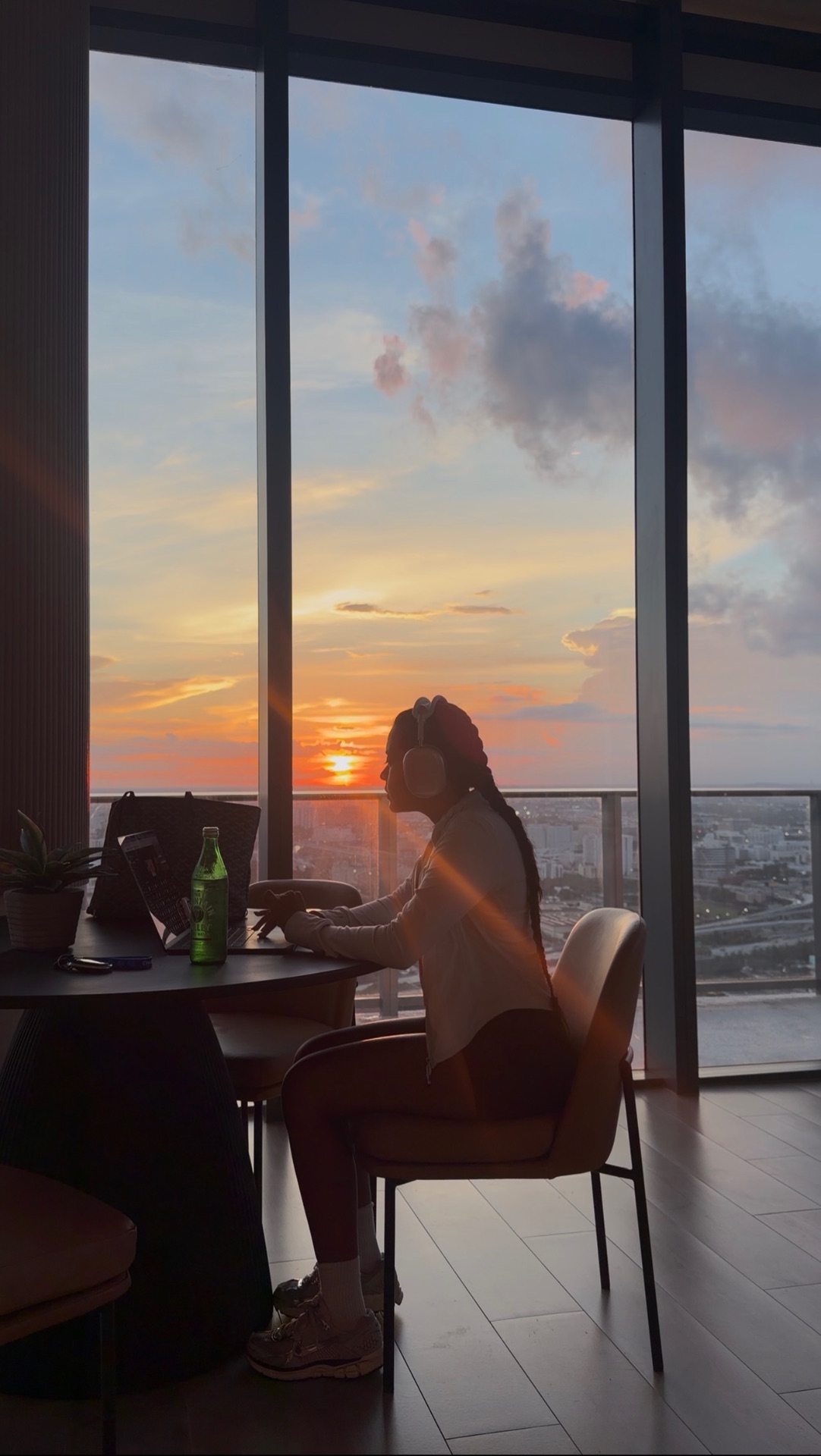 Alicia working at her laptop beside a sunset view