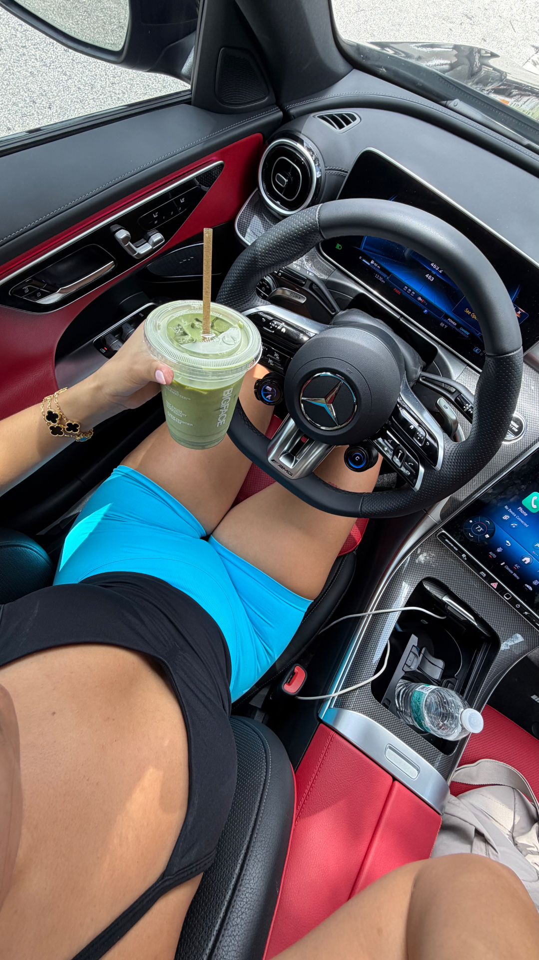 Alicia holding a green drink inside a Mercedes